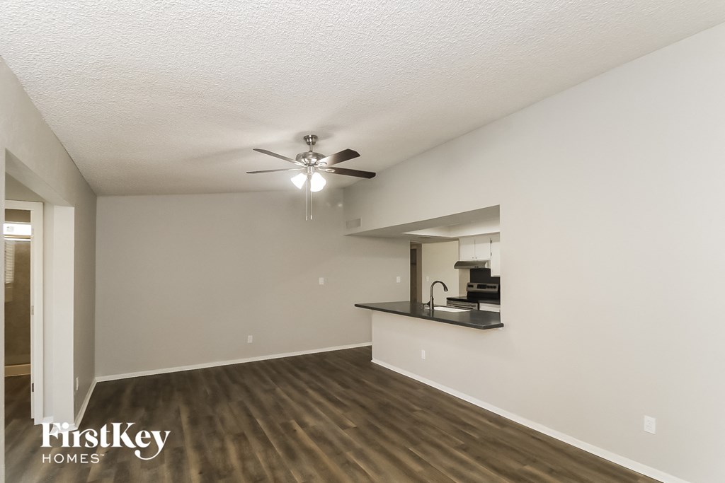 a living room with a kitchen and a ceiling fan