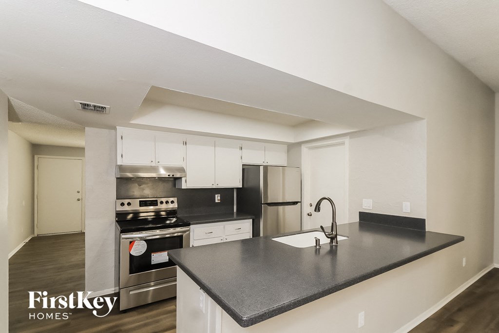 a kitchen with white cabinets and a black counter top