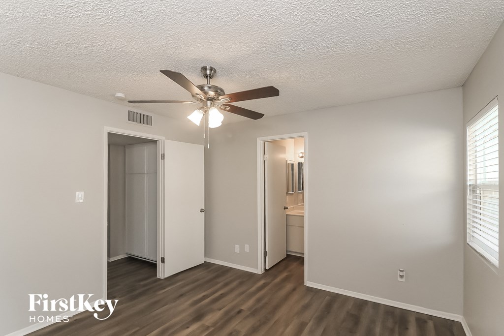 a living room with a ceiling fan and a door to a bathroom