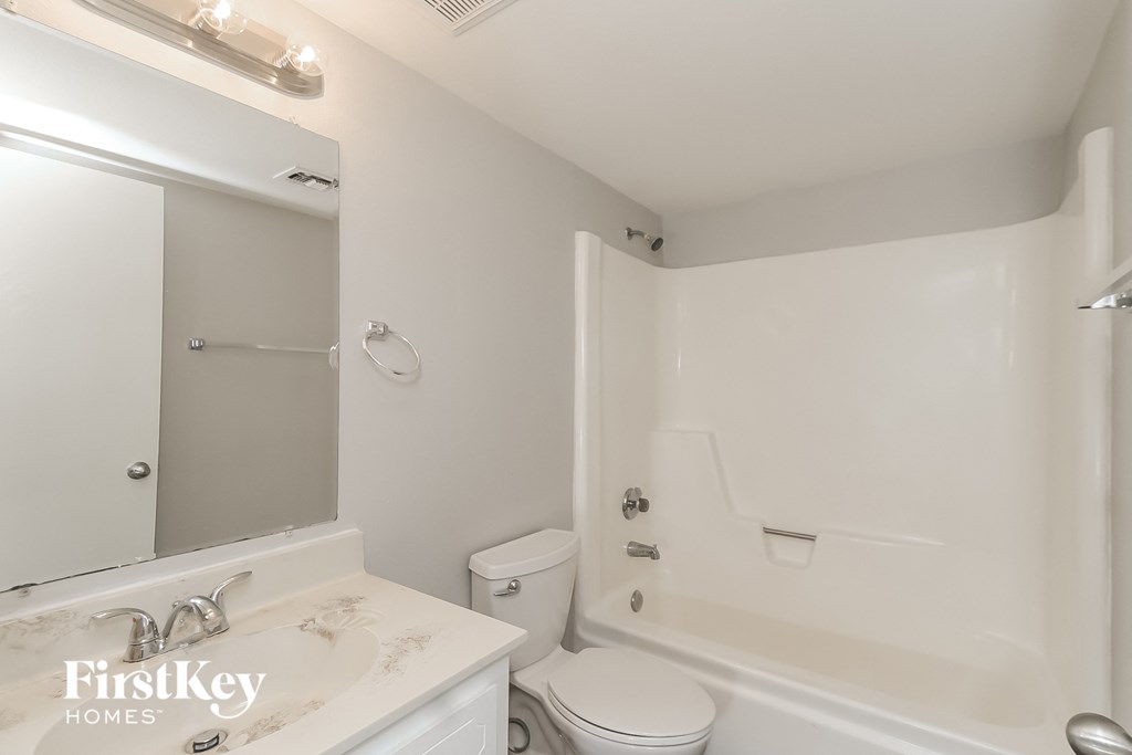 a white bathroom with a white toilet and a tub and a sink