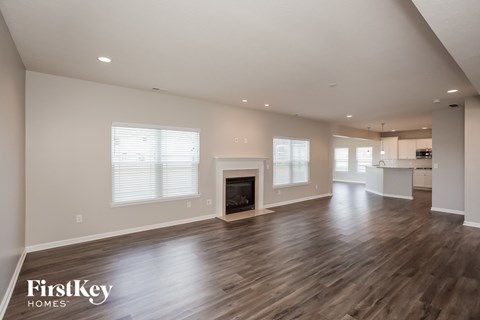 A spacious living room with wood flooring and a fireplace.