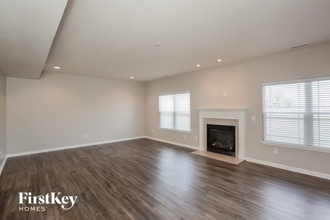A spacious room with a fireplace and wooden flooring.