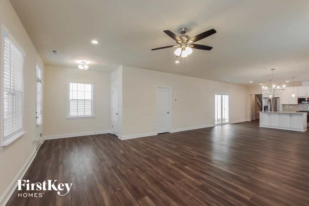 an empty living room with a ceiling fan and wood flooring