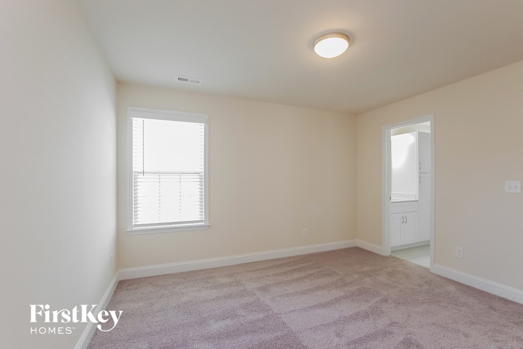 a spacious living room with carpet and a door to the bathroom