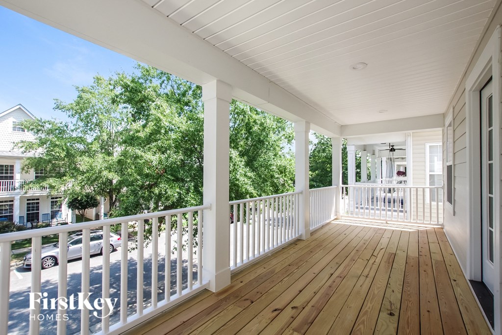 a covered porch with wood floors and white railings