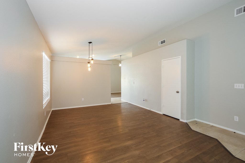 the living room and dining room of an apartment with wood floors and white walls