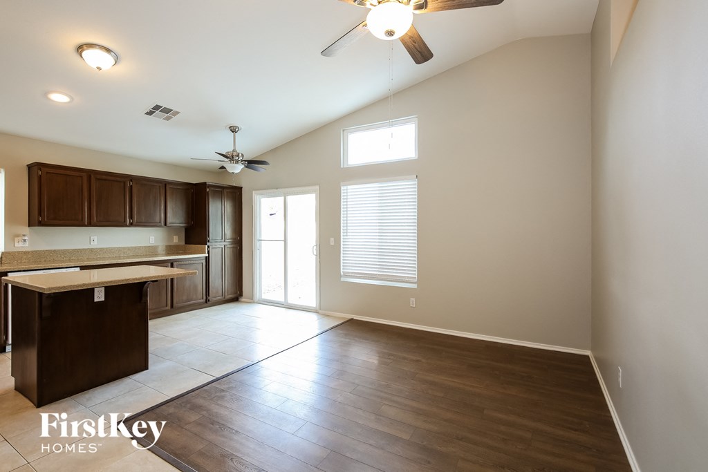 an empty kitchen and living room with wood flooring and a ceiling fan