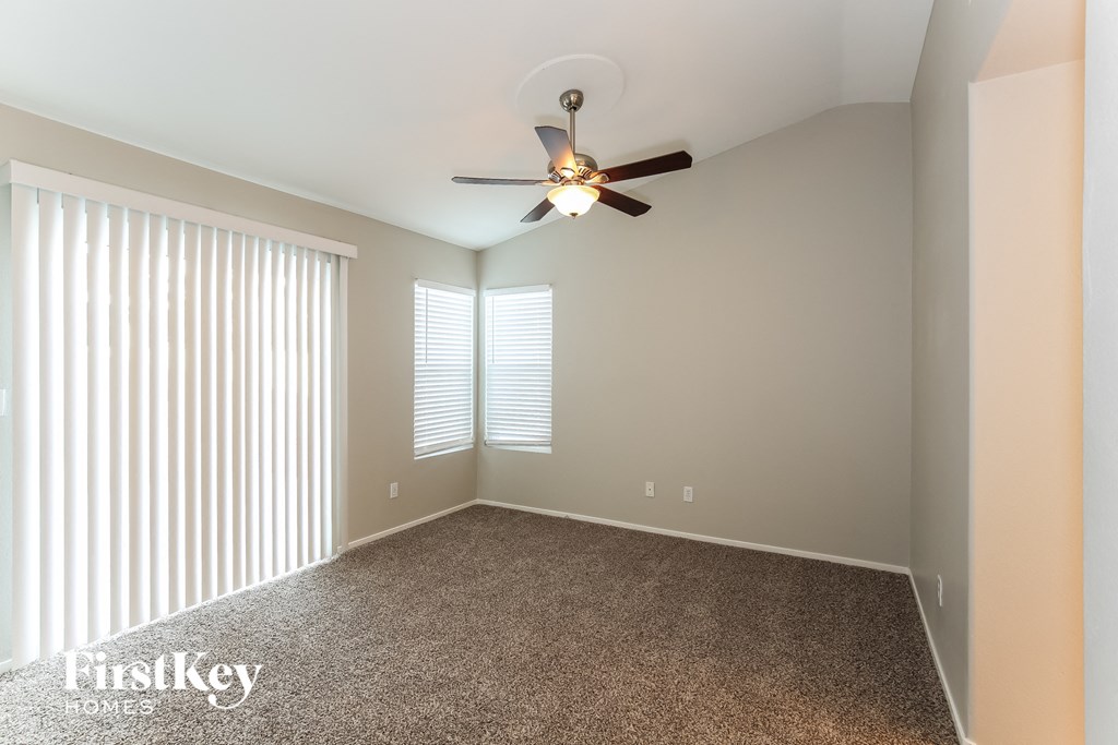 an empty living room with a ceiling fan and blinds