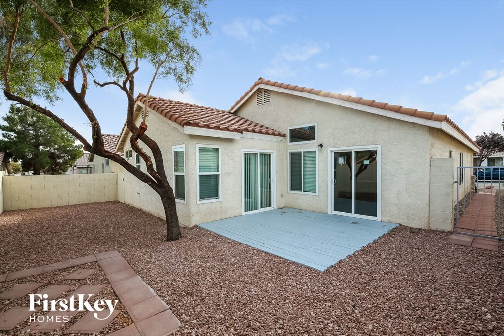 a white house with a tree and a blue patio