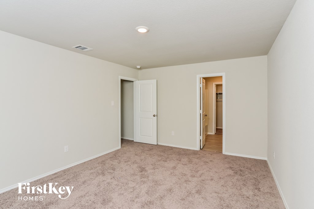 a bedroom with white walls and carpet and a door to a hallway