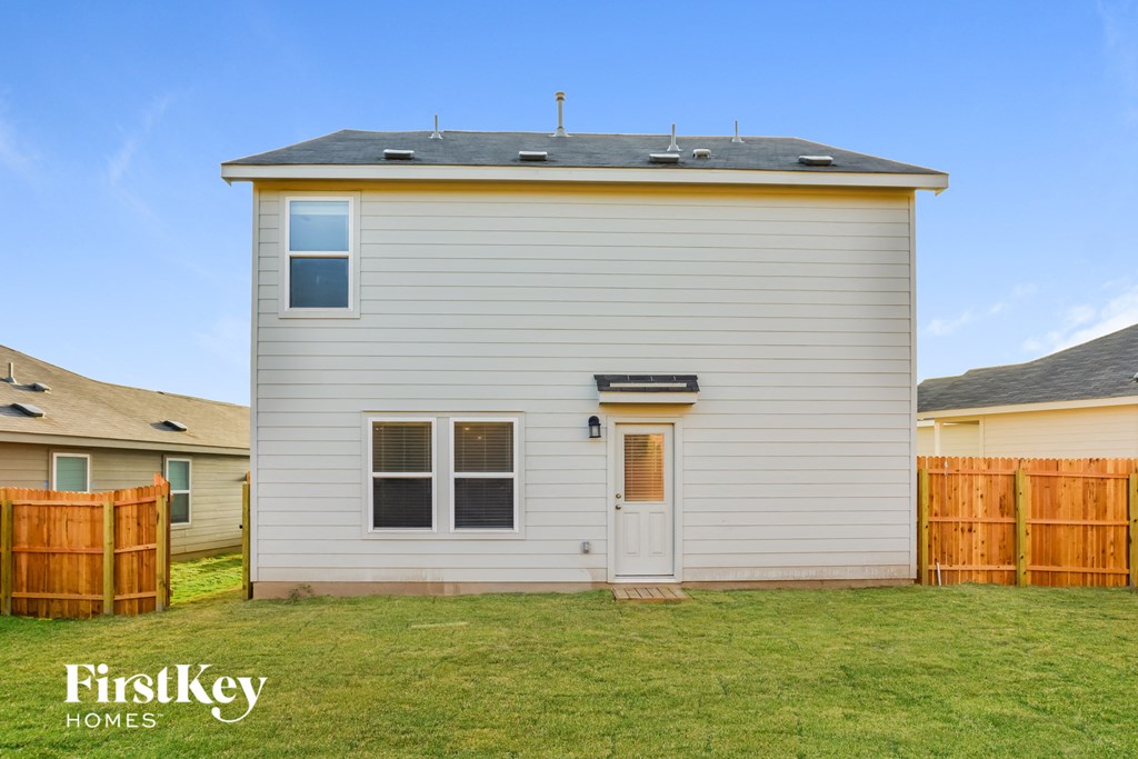 a small white house with a backyard and a wooden fence