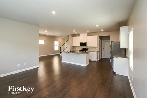 an open kitchen and living room with wood flooring and white cabinets
