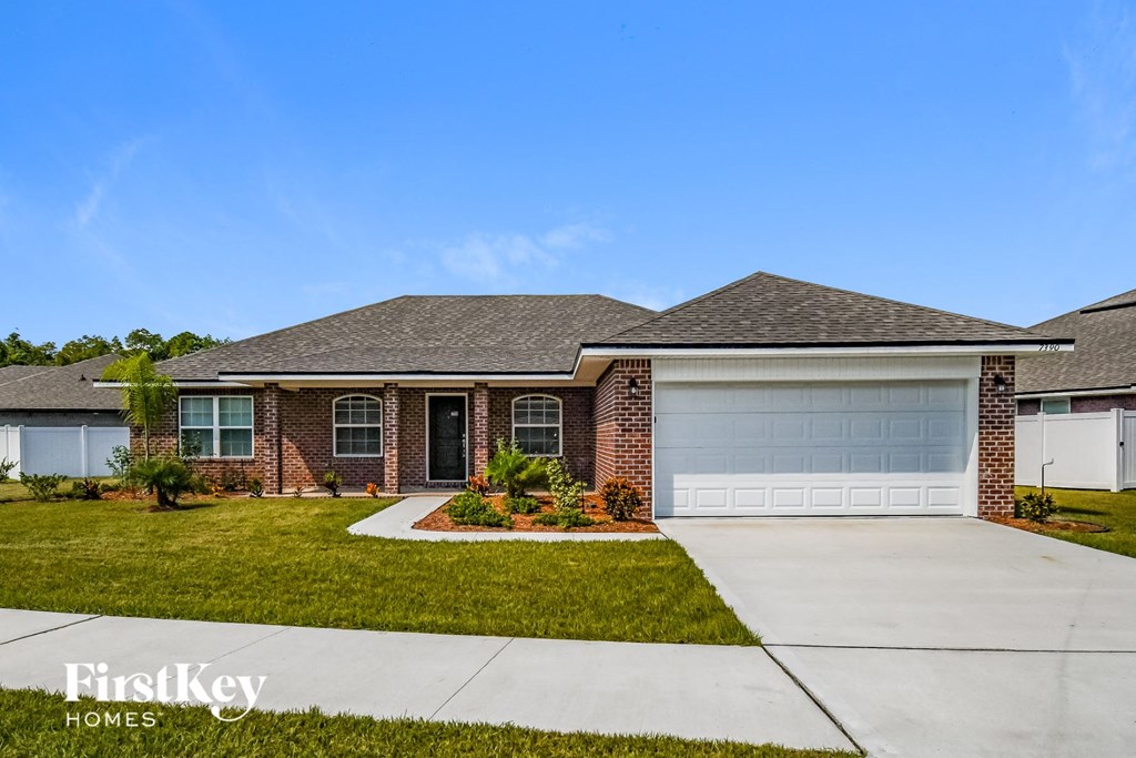 a brick house with a garage door and a lawn