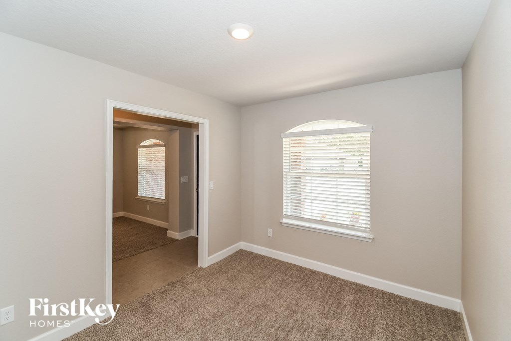 a bedroom with a carpeted floor and a door to a hallway