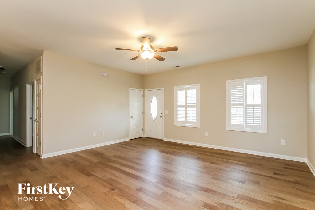 an empty living room with wood floors and a ceiling fan
