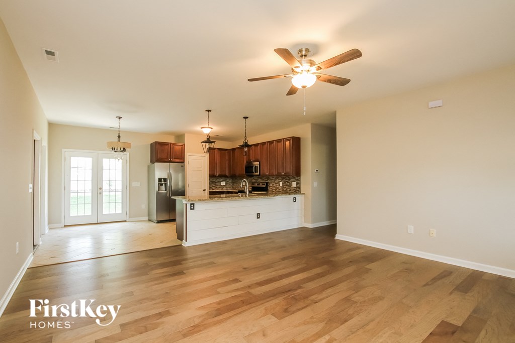 an open kitchen and living room with wood flooring and a ceiling fan