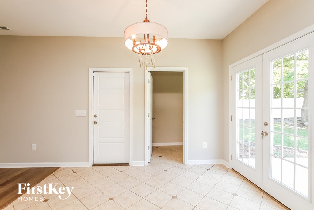 an empty dining room with two doors and a chandelier