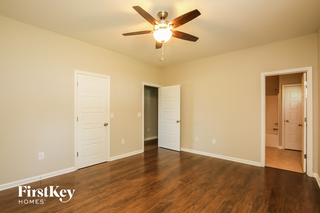 an empty living room with wood floors and a ceiling fan
