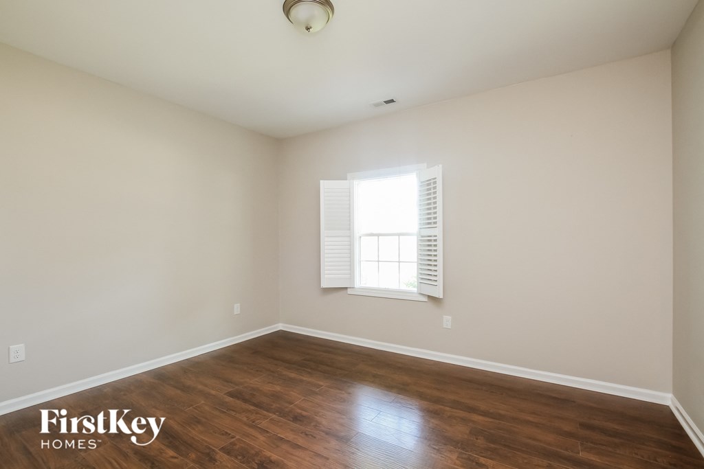 a living room with wood floors and a window and white walls