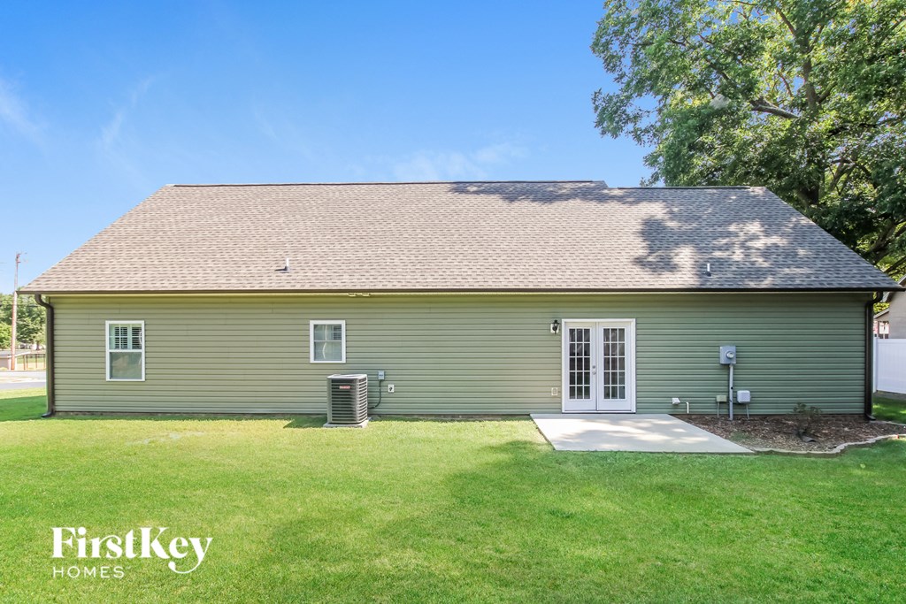 front view of a green house with a yard and a backdoor