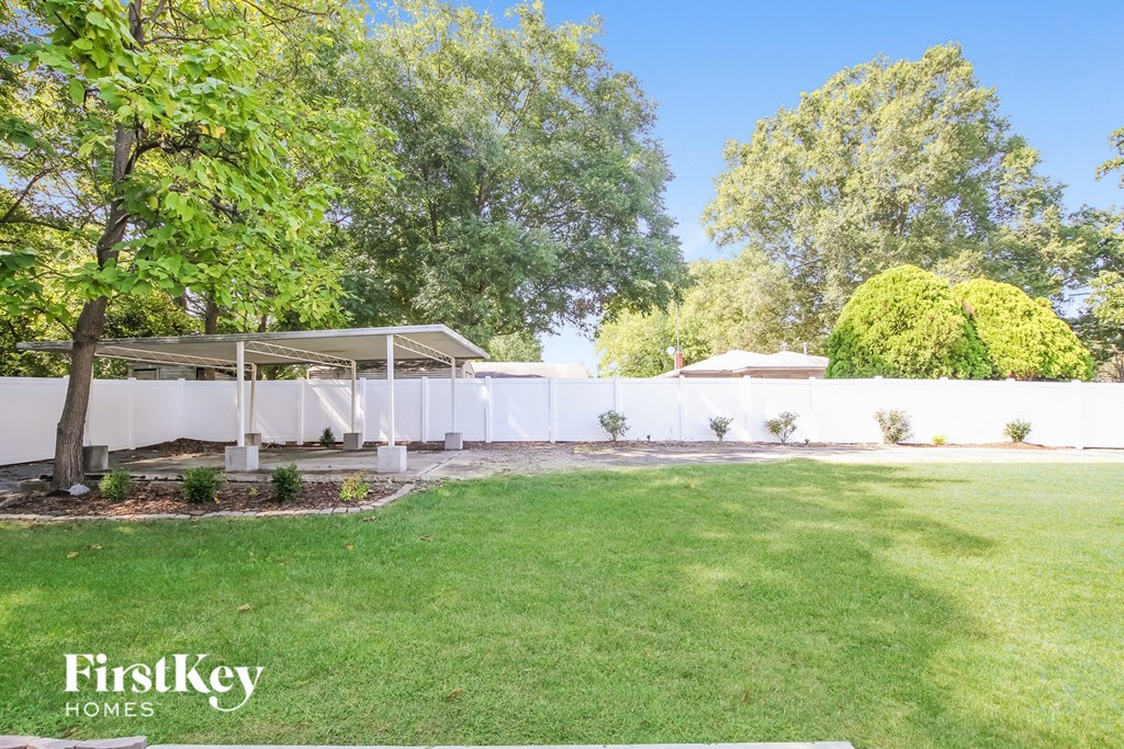 a backyard with a grass lawn and a white fence