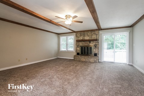 A spacious room with a fireplace and a ceiling fan.
