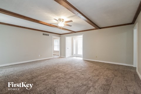 A spacious room with a carpeted floor and a ceiling fan.