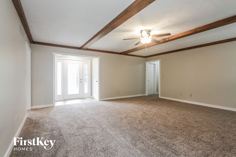 A spacious room with a carpeted floor and a ceiling fan.