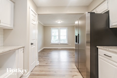 A kitchen with a black refrigerator and white cabinets.