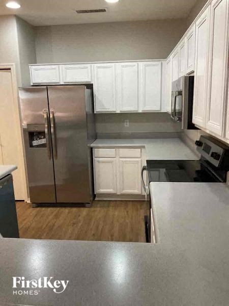A kitchen with a stainless steel refrigerator and white cabinets.