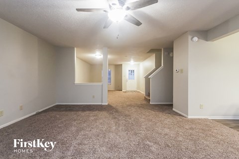 a spacious living room with carpet and a ceiling fan