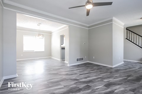 an empty living room with a ceiling fan and a window