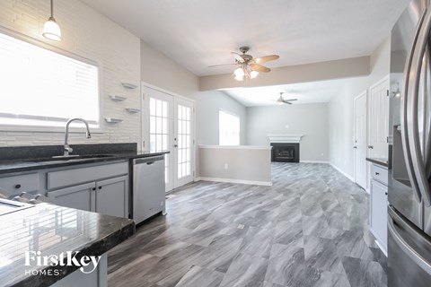 a kitchen and living room with a fireplace and a ceiling fan