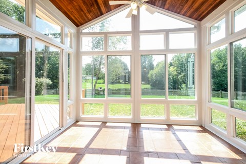 a sun room with large windows and a wooden ceiling