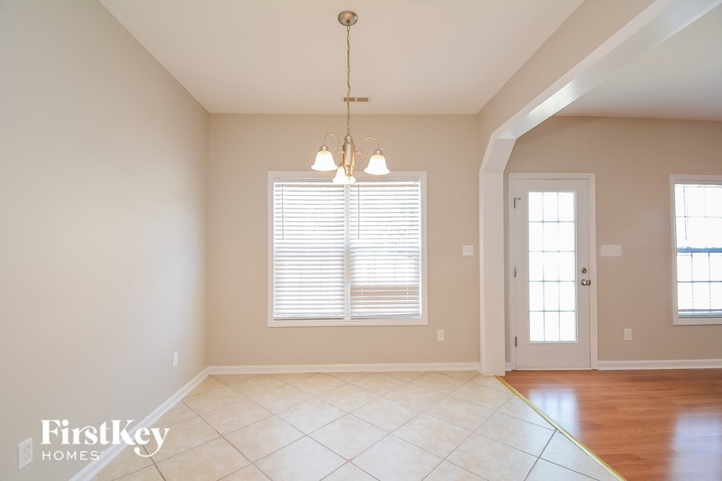 an empty dining room with a window and a chandelier