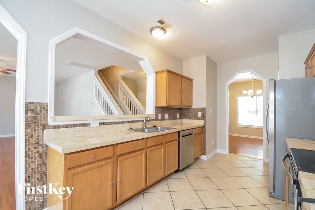 a kitchen with a sink and a refrigerator and a staircase