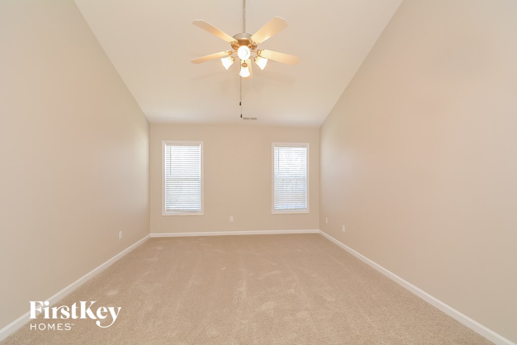 a spacious living room with beige carpet and a ceiling fan