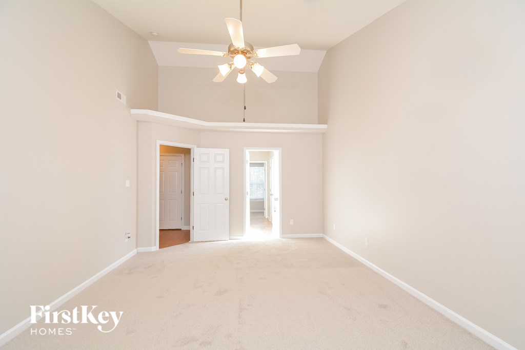 a spacious living room with white walls and a ceiling fan