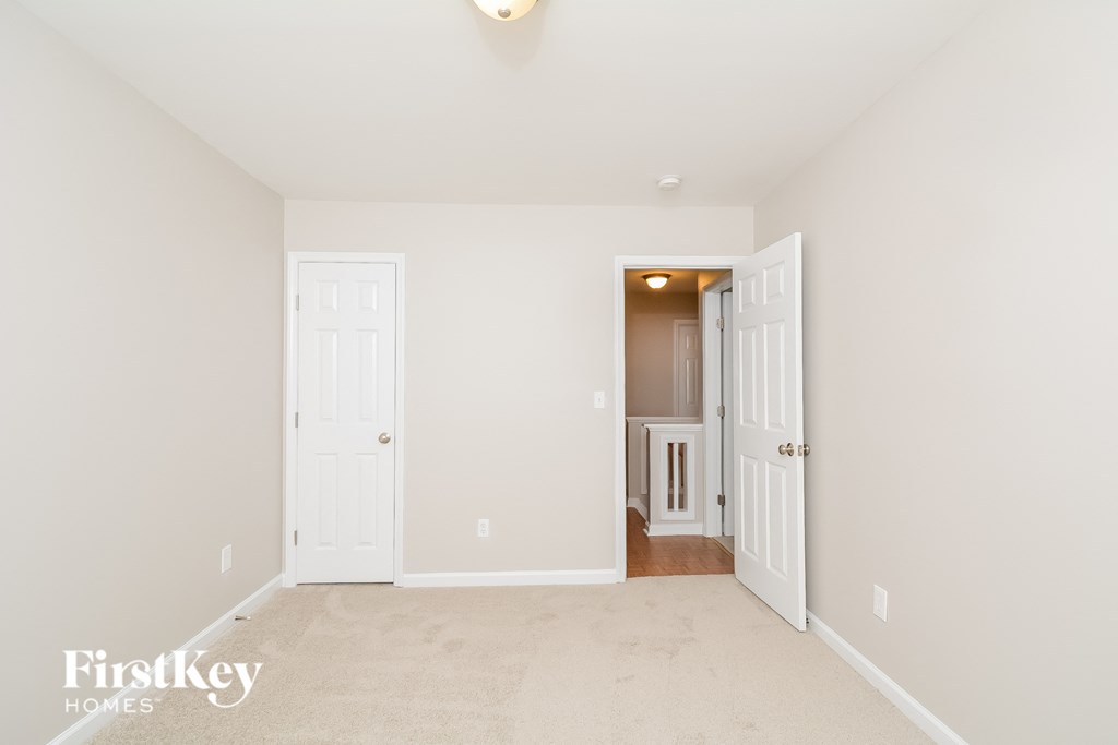 a bedroom with two doors and a carpeted floor and a hallway with a door