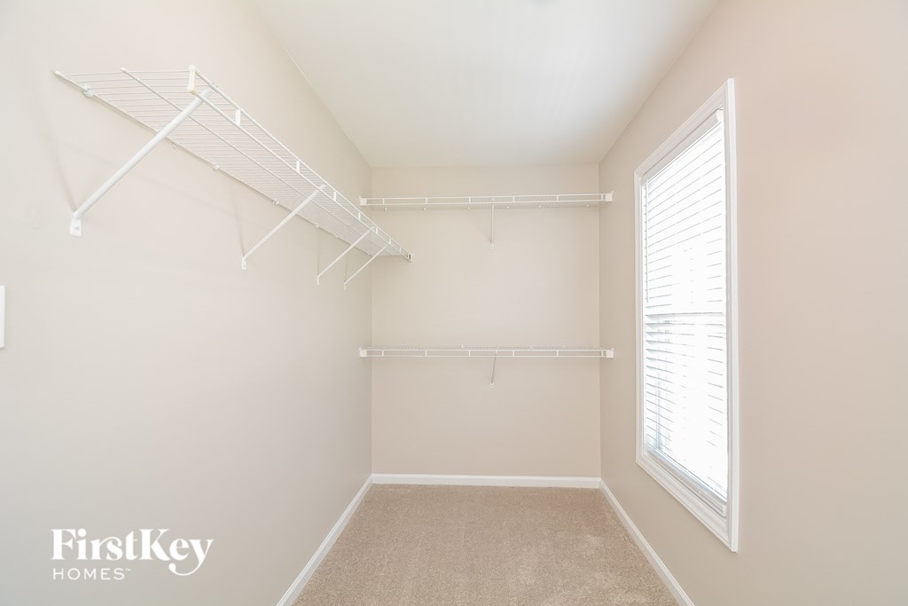 a spacious closet with white shelves and a window