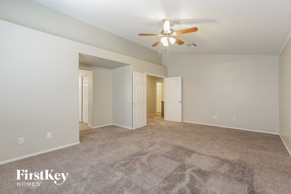 a spacious living room with carpet and a ceiling fan