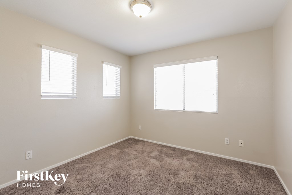 a bedroom with carpet and two windows