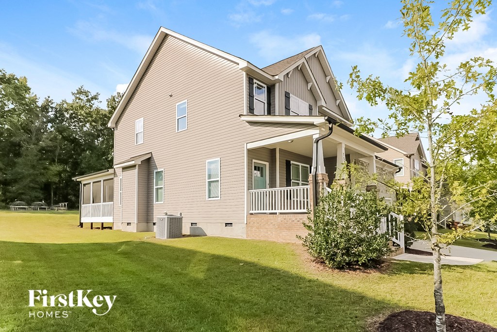 a beige house with a porch and a lawn