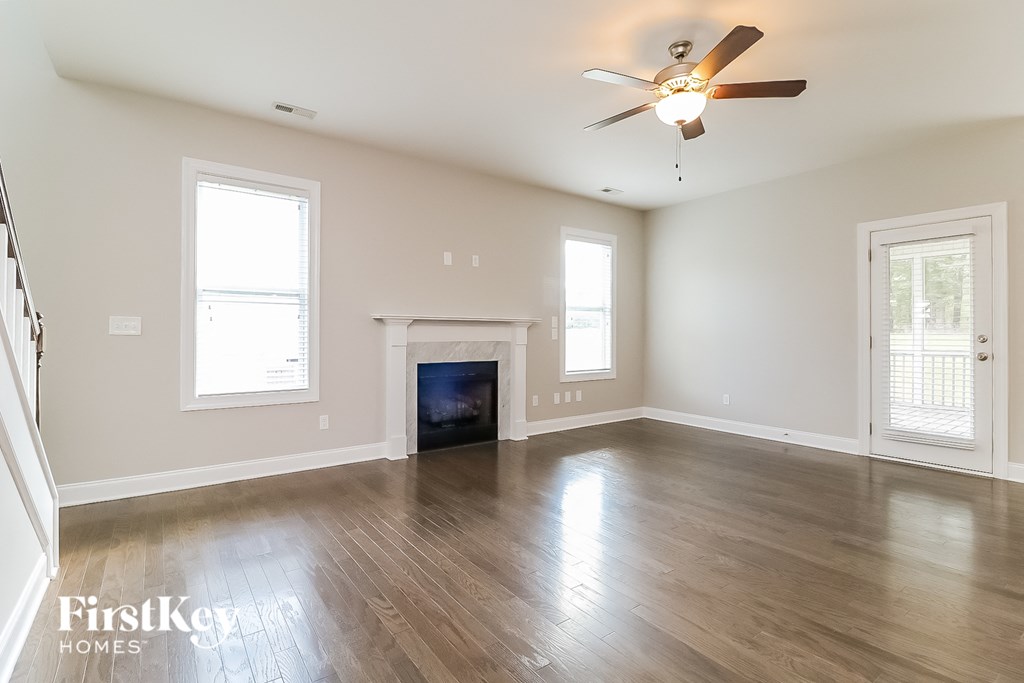 an empty living room with a fireplace and a ceiling fan