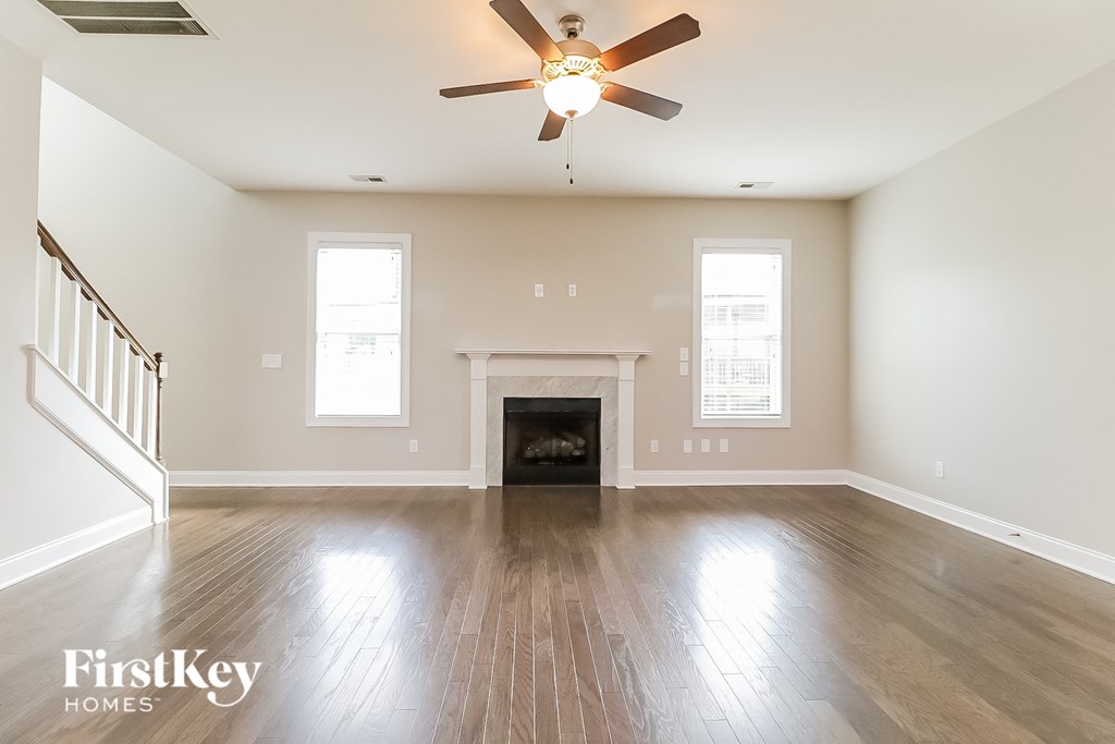 an empty living room with a ceiling fan and a fireplace