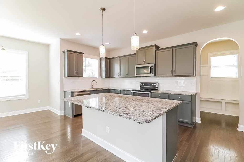 a kitchen with gray cabinets and a marble counter top