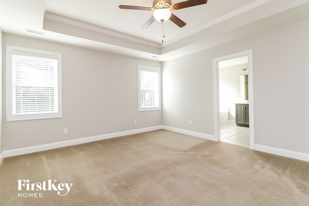 a empty living room with a ceiling fan and a carpet