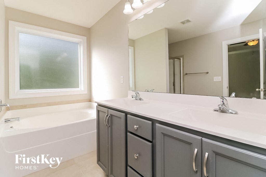 a bathroom with two sinks and a tub and a large mirror