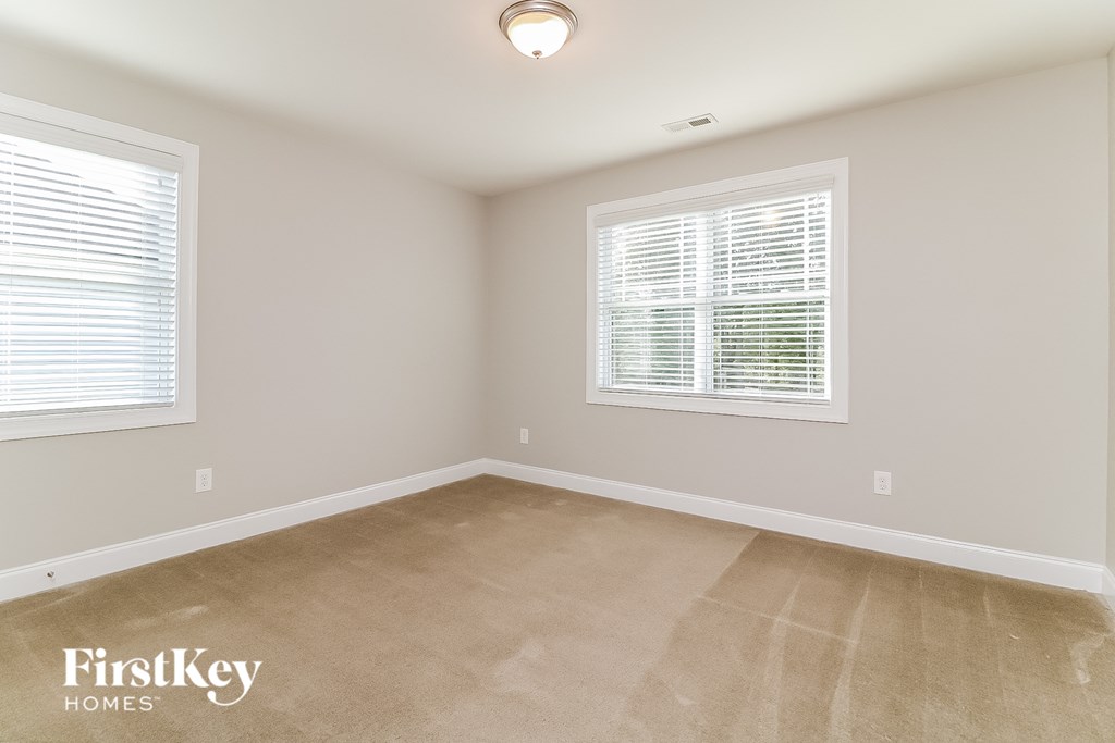 a bedroom with a carpeted floor and two windows
