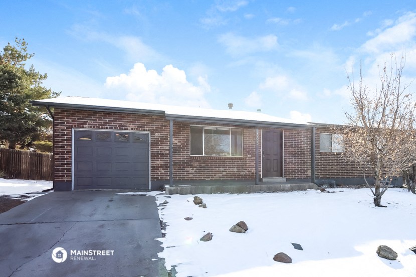 a brick house with a garage in the snow